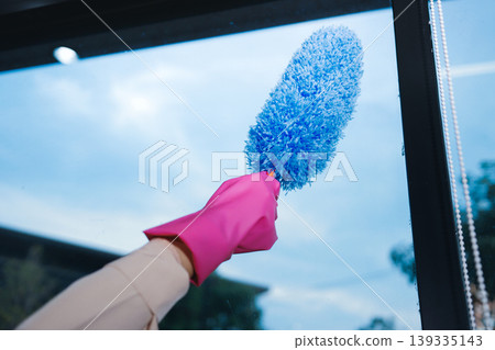 Person cleaning the room, cleaning staff is using cloth and spraying disinfectant to wipe the tables in the company office room. Cleaning staff. Maintaining cleanliness in the organization. Person cleaning the room, cleaning staff is using cloth and spraying disinfectant to wipe the tables in the company office room. Cleaning staff. Maintaining cleanliness in the organization. 139335143