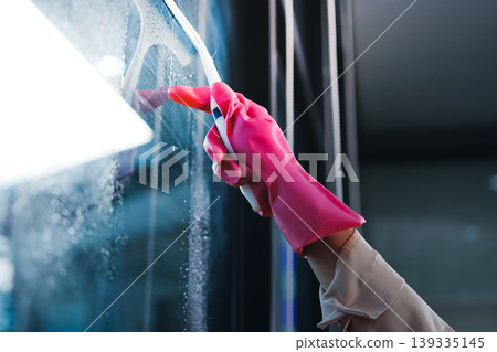 Person cleaning the room, cleaning staff is using cloth and spraying disinfectant to wipe the tables in the company office room. Cleaning staff. Maintaining cleanliness in the organization. Person cleaning the room, cleaning staff is using cloth and spraying disinfectant to wipe the tables in the company office room. Cleaning staff. Maintaining cleanliness in the organization. 139335145