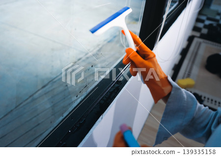 Person cleaning the room, cleaning staff is using cloth and spraying disinfectant to wipe the tables in the company office room. Cleaning staff. Maintaining cleanliness in the organization. Person cleaning the room, cleaning staff is using cloth and spraying disinfectant to wipe the tables in the company office room. Cleaning staff. Maintaining cleanliness in the organization. 139335158