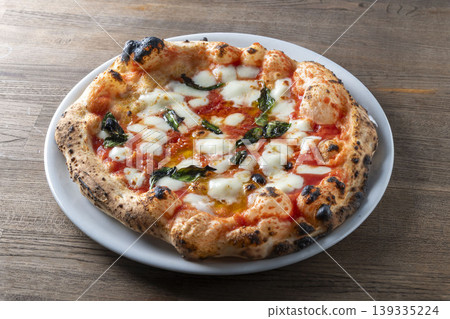 Freshly baked and topped with plenty of delicious cheese, this is a Margherita pizza, an Italian dish. Freshly baked and topped with plenty of delicious cheese, this is a Margherita pizza, an Italian dish. 139335224