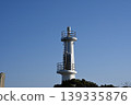 A photograph of a white lighthouse standing tall against a clear blue sky. 139335876