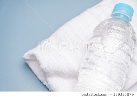Close-up of a plastic bottle and towel against a blue background. Close-up of a plastic bottle and towel against a blue background. 139335879