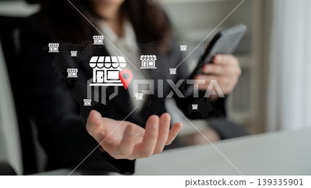 Business owner analyzing location data on mobile device with virtual store icons to enhance marketing strategies in a digital landscape Gantry Business owner analyzing location data on mobile device with virtual store icons to enhance marketing strategies in a digital landscape Gantry 139335901