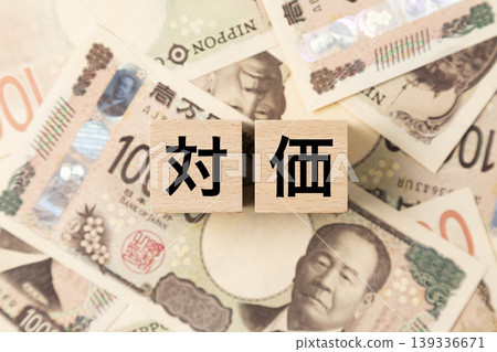 A block with the word "compensation" written on it and lots of 10,000 yen bills. A block with the word "compensation" written on it and lots of 10,000 yen bills. 139336671