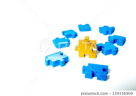 One golden jigsaw puzzle piece standing out from a group of blue pieces on white. Concept for leadership, individuality, business solution, and being unique. High quality studio shot with space. One golden jigsaw puzzle piece standing out from a group of blue pieces on white. Concept for leadership, individuality, business solution, and being unique. High quality studio shot with space. 139336909