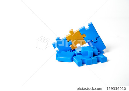 One unique gold puzzle piece standing out from a pile of blue jigsaw pieces on a white background. Representing leadership, individuality, excellence, and the perfect fit for a business solution. One unique gold puzzle piece standing out from a pile of blue jigsaw pieces on a white background. Representing leadership, individuality, excellence, and the perfect fit for a business solution. 139336910