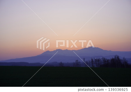 The sunrise, tinged with purple and orange, and the silhouette of the Daisetsuzan Mountains in Hokkaido. The sunrise, tinged with purple and orange, and the silhouette of the Daisetsuzan Mountains in Hokkaido. 139336925