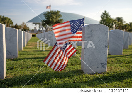 Army veteran cemetery with white headstones and USA flag. Tombs of retired military soldiers. Memorial Day concept Army veteran cemetery with white headstones and USA flag. Tombs of retired military soldiers. Memorial Day concept 139337525
