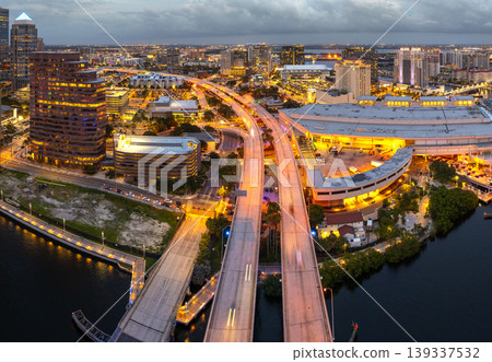 American city skyline with brightly illuminated high commercial buildings and bridge over Hillsborough river. Night urban landscape of downtown district of Tampa in Florida, USA. American city skyline with brightly illuminated high commercial buildings and bridge over Hillsborough river. Night urban landscape of downtown district of Tampa in Florida, USA. 139337532