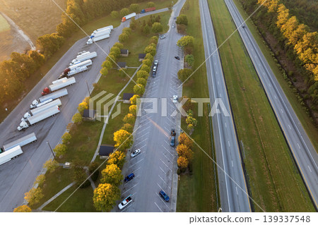 Aerial view of truck stop rest area near busy American interstate freeway. Recreational place during delivering cargo Aerial view of truck stop rest area near busy American interstate freeway. Recreational place during delivering cargo 139337548