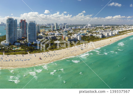 Aerial view of South Beach sandy surface with tourists relaxing on hot Florida sun. Miami Beach city with high luxury hotels and condos. Tourism infrastructure in southern USA Aerial view of South Beach sandy surface with tourists relaxing on hot Florida sun. Miami Beach city with high luxury hotels and condos. Tourism infrastructure in southern USA 139337567