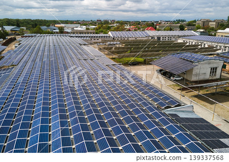 Aerial view of solar power plant with blue photovoltaic panels mounted on industrial building roof for producing green ecological electricity. Production of sustainable energy concept. Aerial view of solar power plant with blue photovoltaic panels mounted on industrial building roof for producing green ecological electricity. Production of sustainable energy concept. 139337568