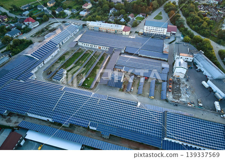 Aerial view of solar power plant with blue photovoltaic panels mounted on industrial building roof for producing green ecological electricity. Production of sustainable energy concept Aerial view of solar power plant with blue photovoltaic panels mounted on industrial building roof for producing green ecological electricity. Production of sustainable energy concept 139337569