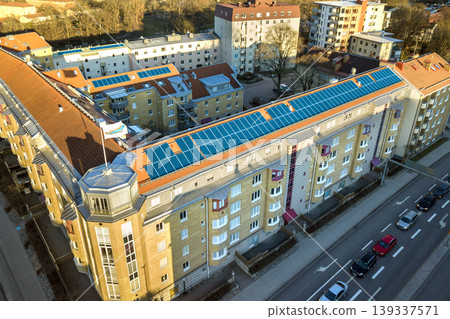 Aerial view of solar photo voltaic panels system on apartment building roof. Renewable ecological green energy production concept. Aerial view of solar photo voltaic panels system on apartment building roof. Renewable ecological green energy production concept. 139337571