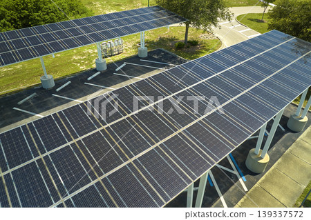 Aerial view of solar panels installed as shade roof over parking lot for parked cars for effective generation of clean electricity. Photovoltaic technology integrated in urban infrastructure Aerial view of solar panels installed as shade roof over parking lot for parked cars for effective generation of clean electricity. Photovoltaic technology integrated in urban infrastructure 139337572