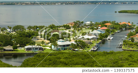 Aerial view of residential suburbs with private homes located near wildlife wetlands with green vegetation on sea shore. Living close to nature concept Aerial view of residential suburbs with private homes located near wildlife wetlands with green vegetation on sea shore. Living close to nature concept 139337575
