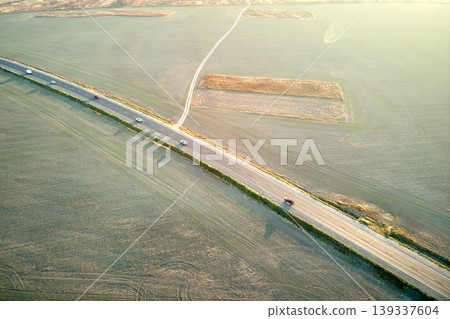 Aerial view of intercity road with fast driving cars at sunset. Top view from drone of highway traffic in evening Aerial view of intercity road with fast driving cars at sunset. Top view from drone of highway traffic in evening 139337604