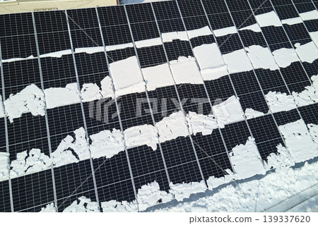 Aerial view of electrical power plant with solar panels covered with snow melting down in winter end for producing clean energy. Concept of low effectivity of renewable electricity in northern region Aerial view of electrical power plant with solar panels covered with snow melting down in winter end for producing clean energy. Concept of low effectivity of renewable electricity in northern region 139337620