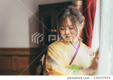 一位身穿振袖和服的 20 歲女子凝視著一棟復古的西式古董豪宅/工作室的窗外。 139337974