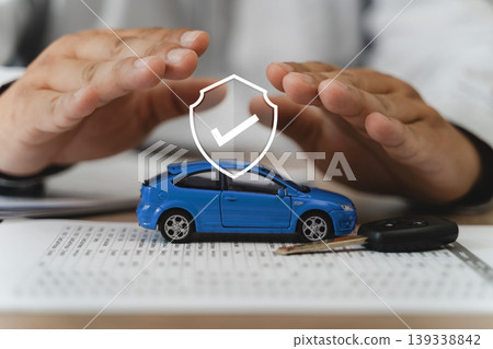 Auto insurance protection and accident prevention concept with two hands shielding blue car model, vehicle key, and policy document with shield checkmark icon, securing comprehensive coverage. Auto insurance protection and accident prevention concept with two hands shielding blue car model, vehicle key, and policy document with shield checkmark icon, securing comprehensive coverage. 139338842