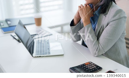 stressed Asian businesswoman hand on chin worried about financial problem thinking solution at office desk with laptop calculator papers planning budget stressed Asian businesswoman hand on chin worried about financial problem thinking solution at office desk with laptop calculator papers planning budget 139340015