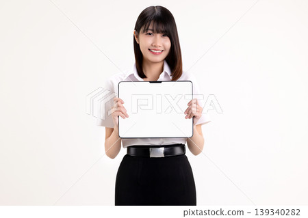 Smiling young Asian woman in student uniform holding digital tablet with blank white screen for mockup. Happy female university student showing tablet computer isolated on white background. Smiling young Asian woman in student uniform holding digital tablet with blank white screen for mockup. Happy female university student showing tablet computer isolated on white background. 139340282