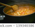 Chef using wooden spoon stirring tomato and bean soup cooking in pot 139340386