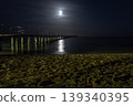 Moon reflecting over pier on beach at night 139340395