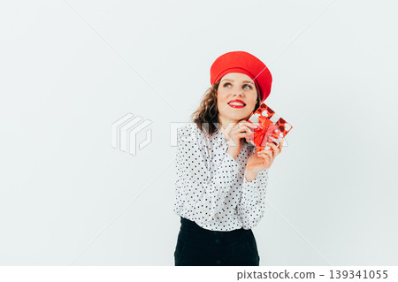 Happy woman with red hat holding wrapped gift Happy woman with red hat holding wrapped gift 139341055