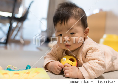 A Japanese baby boy chewing on a toy ball. A Japanese baby boy chewing on a toy ball. 139341087
