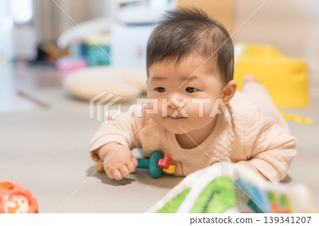 A Japanese baby boy reaches for a toy ball on a playmat. A Japanese baby boy reaches for a toy ball on a playmat. 139341207