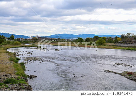 The view of Katsura River at autumn from Togetsukyo Bridge, Kyoto, Japan. A well-known place of scenic beauty in the western hills of Kyoto. Nature and travel concept. The view of Katsura River at autumn from Togetsukyo Bridge, Kyoto, Japan. A well-known place of scenic beauty in the western hills of Kyoto. Nature and travel concept. 139341475