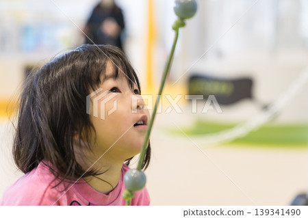 A young Japanese girl playing with exhibits at a science museum. A young Japanese girl playing with exhibits at a science museum. 139341490