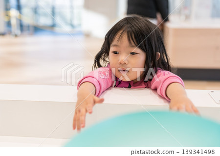 A young Japanese girl playing with exhibits at a science museum. A young Japanese girl playing with exhibits at a science museum. 139341498