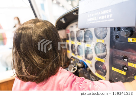 A young Japanese girl operating an airplane cockpit exhibit at a science museum. A young Japanese girl operating an airplane cockpit exhibit at a science museum. 139341538
