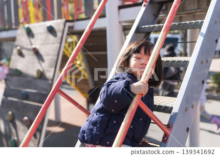 A Japanese toddler girl slides down a slide in a park. A Japanese toddler girl slides down a slide in a park. 139341692