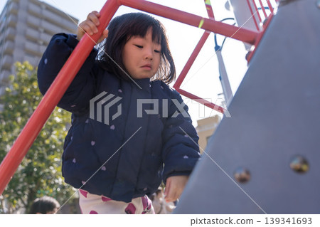 A Japanese toddler girl slides down a slide in a park. A Japanese toddler girl slides down a slide in a park. 139341693