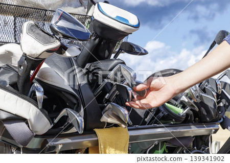The hands of a player selecting an iron from their golf bag The hands of a player selecting an iron from their golf bag 139341902