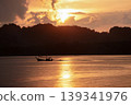 Silhouette of long-tail boat floating in the calm sea with silhouette of mountain and cloudy twilight sky in background 139341976
