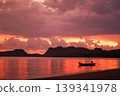 Silhouette of long-tail boat floating in the calm sea with silhouette of mountain and cloudy twilight sky in background 139341978