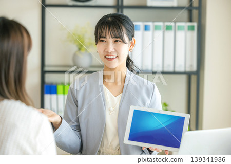 A businesswoman presenting a proposal while holding a tablet. 139341986