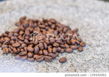 Close-up of roasted coffee beans piled on a stone stand; shallow depth of field. 139342001