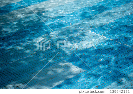 Background image: A pool surface sparkling in the sunlight - blue and light blue. Background image: A pool surface sparkling in the sunlight - blue and light blue. 139342151