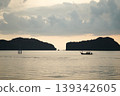 Silhouette of long-tail boat floating in the calm sea in front of the space between two islands 139342605