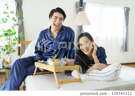 A young Japanese celebrity couple smiling side-by-side in bed in the morning. A young Japanese celebrity couple smiling side-by-side in bed in the morning. 139343112