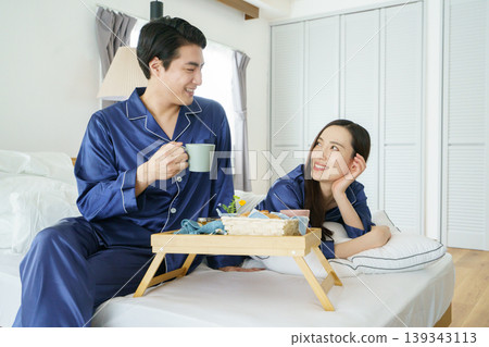 A young Japanese celebrity couple smiling side-by-side in bed in the morning. A young Japanese celebrity couple smiling side-by-side in bed in the morning. 139343113