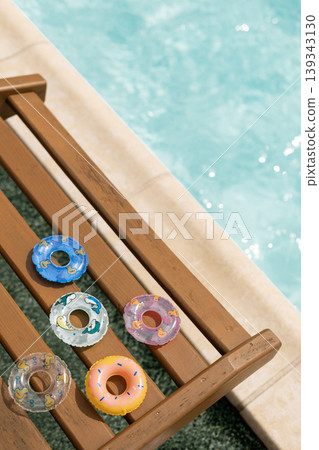 Summer fun concept with colorful mini floats on a poolside chair near sparkling water 139343130