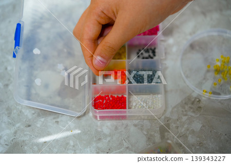 A creative girl is engaged in beadwork. Hobby and small business concept A creative girl is engaged in beadwork. Hobby and small business concept 139343227