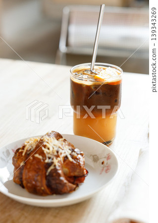Cup of creation black coffee drink and orange juice with croissant on wooden table by the window. Cup of creation black coffee drink and orange juice with croissant on wooden table by the window. 139343269