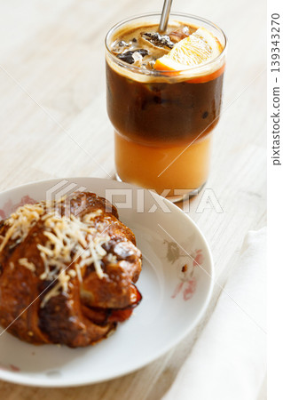 Cup of creation black coffee drink and orange juice with croissant on wooden table by the window. Cup of creation black coffee drink and orange juice with croissant on wooden table by the window. 139343270